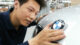 A person examines a BMW emblem on a car in an automotive workshop, highlighting attention to detail in vehicle production.