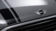 Close-up of a silver car hood featuring the MINI emblem and black racing stripes, showcasing sleek, modern automotive design.