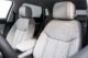Gray leather car interior with orange stitching, showcasing front seats and center console inside a vehicle, viewed in bright, even lighting.