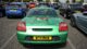 A green sports car is parked in a busy lot, surrounded by various vehicles on a sunny day. Plates indicate UK registration.