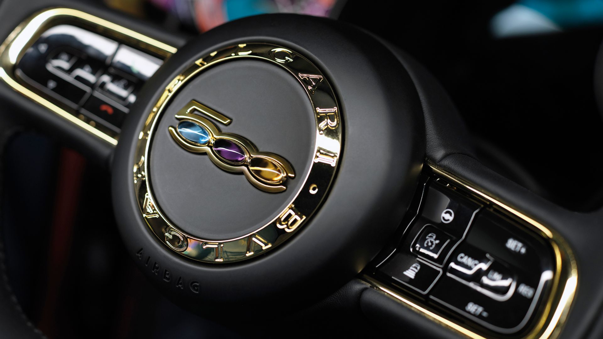 Close-up of a Fiat steering wheel featuring the Bulgari logo and colorful details, highlighting luxury design elements and modern controls.